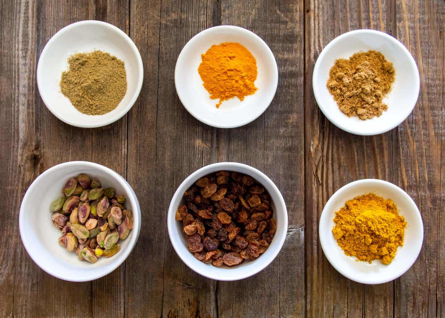 spices raisins and pistachios in white bowls