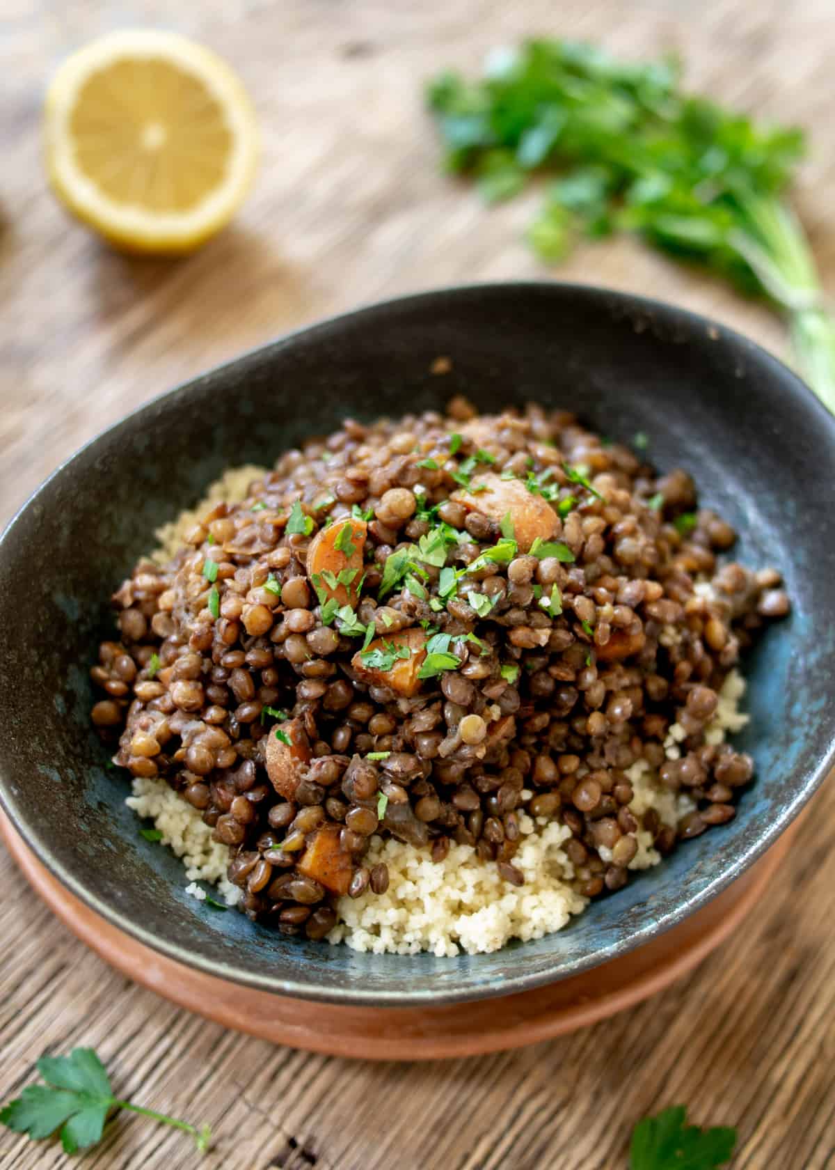 Close up of lentil stew on couscous with parsley and lemon in background