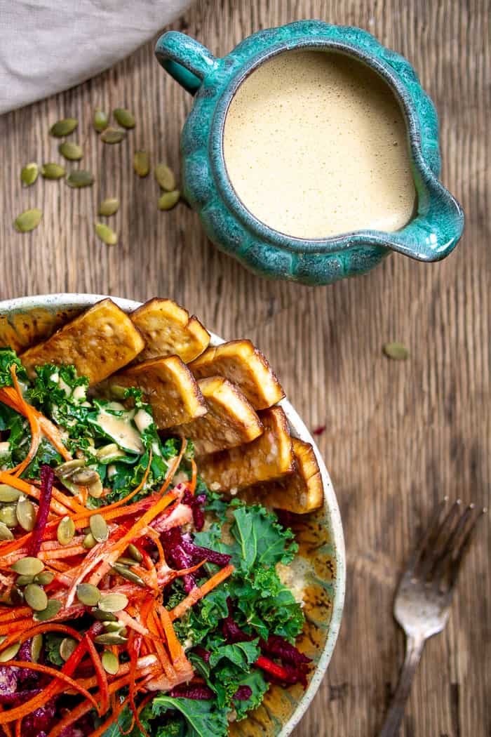 Kale Quinoa Salad on Wooden Background with Dressing in Blue Bowl