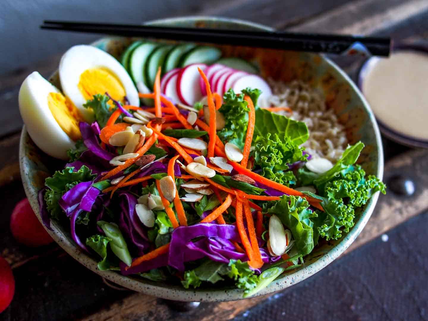 Close Up of Salad with Boiled Eggs and Miso Tahini Dressing On Side