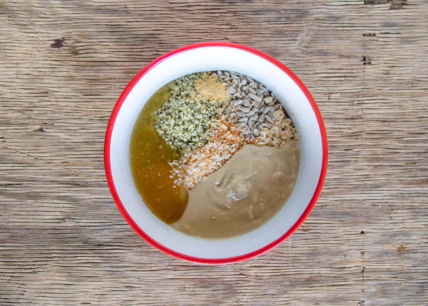 Ingredients for no-bake energy balls in red and white bowl