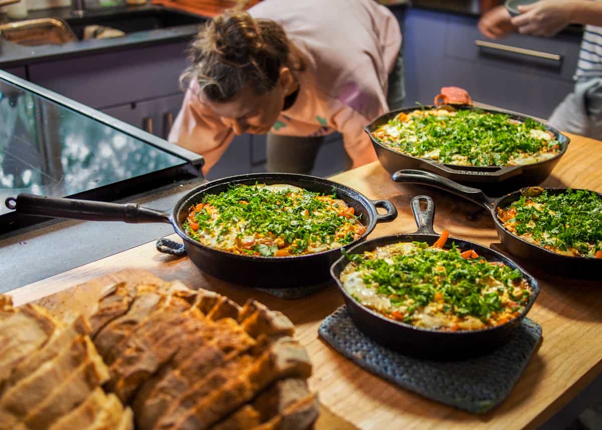 Bread and 4 cast irons of shakshouka topped with parsley