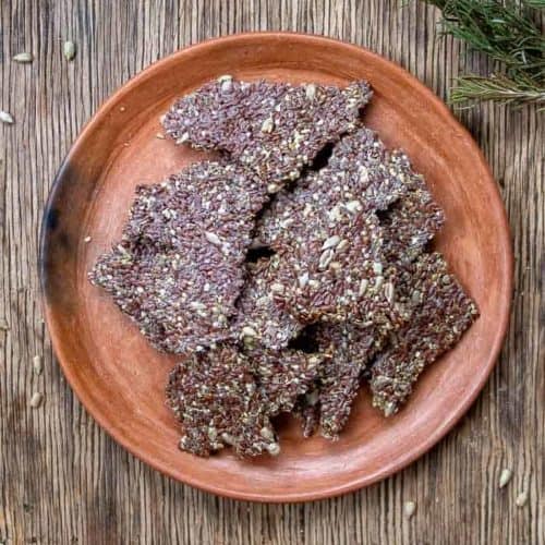 Keto Seed Crackers on Brown Ceramic Plate with Rosemary On Side