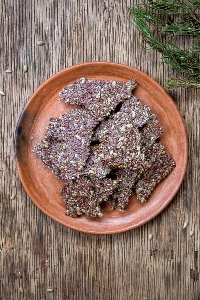 Keto Seed Crackers on Brown Ceramic Plate with Rosemary On Side