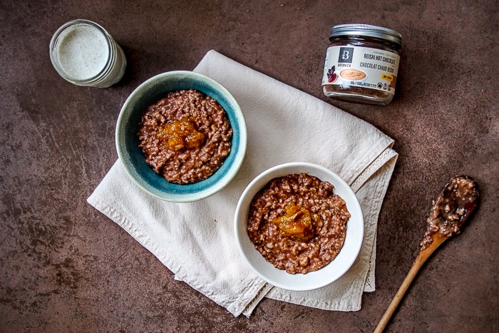 Orange Chocolate Oatmeal in Bowls on White Linen with Wooden Spoon