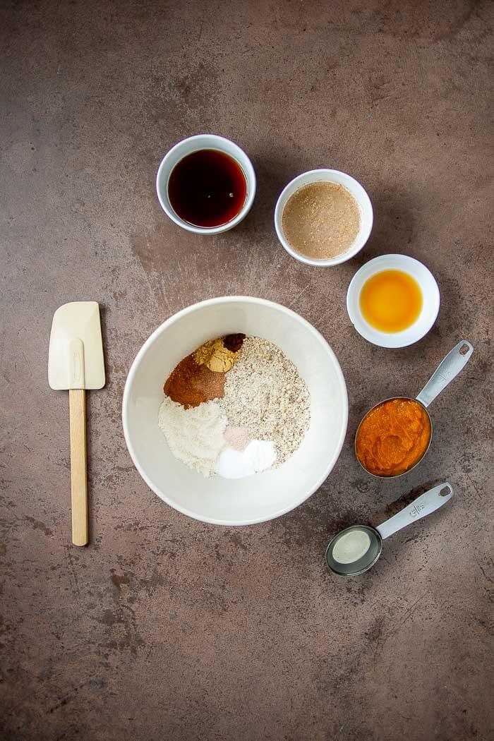 Dry Ingredients for Soft Pumpkin Cookies in a White Bowl. Wet Ingredients In smaller Bowls.