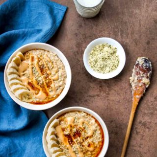 high protein steel-cut oats in white bowls with blue linen napkin and wooden spoon