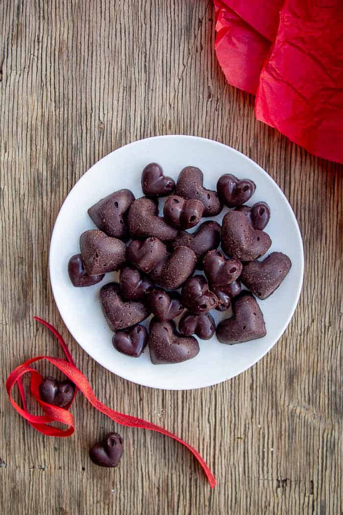 Raw Chocolate Hearts on White Plate on Wooden Background