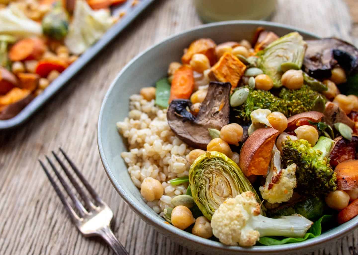 close up of bowl with roasted vegetables and chickpeas on top of brown rice