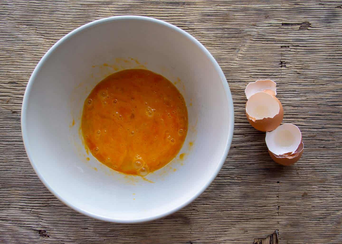 Whisked eggs in white bowl