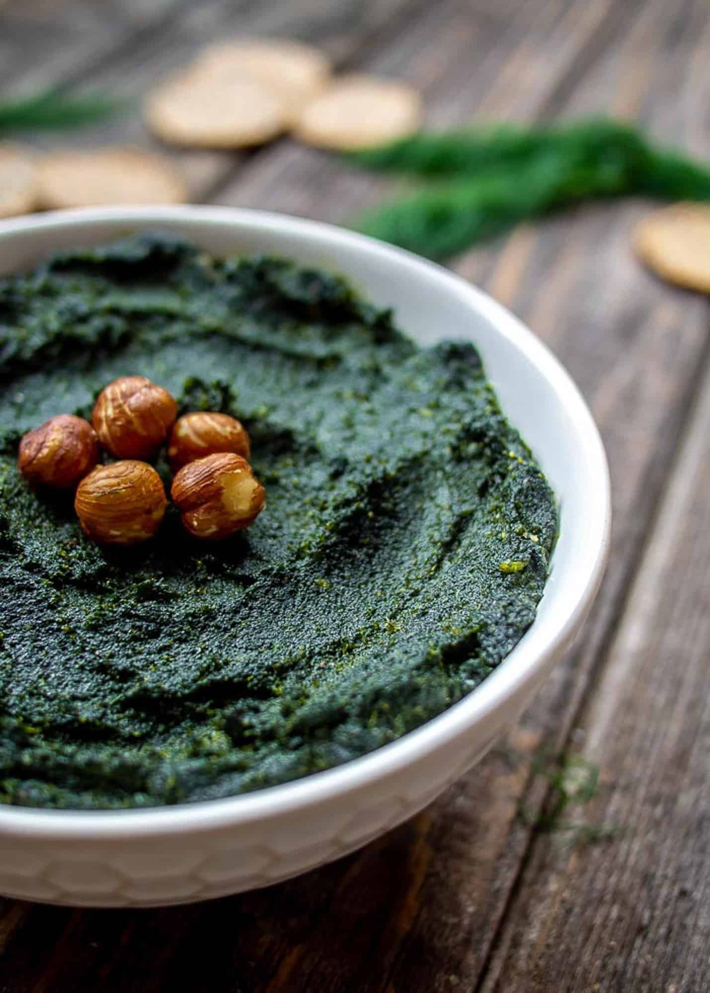 pesto in white bowl with hazelnuts on top